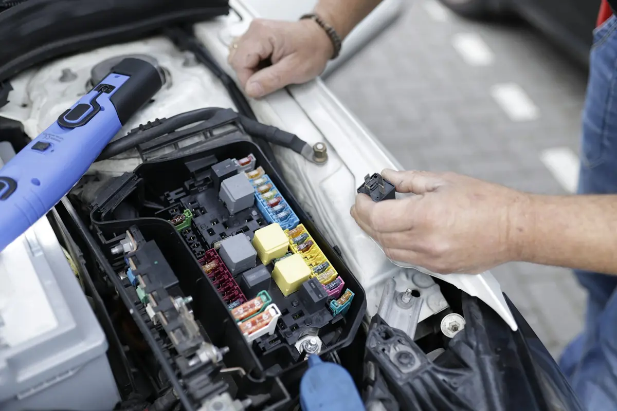 Mecânico verificando a caixa de fusíveis no compartimento do motor